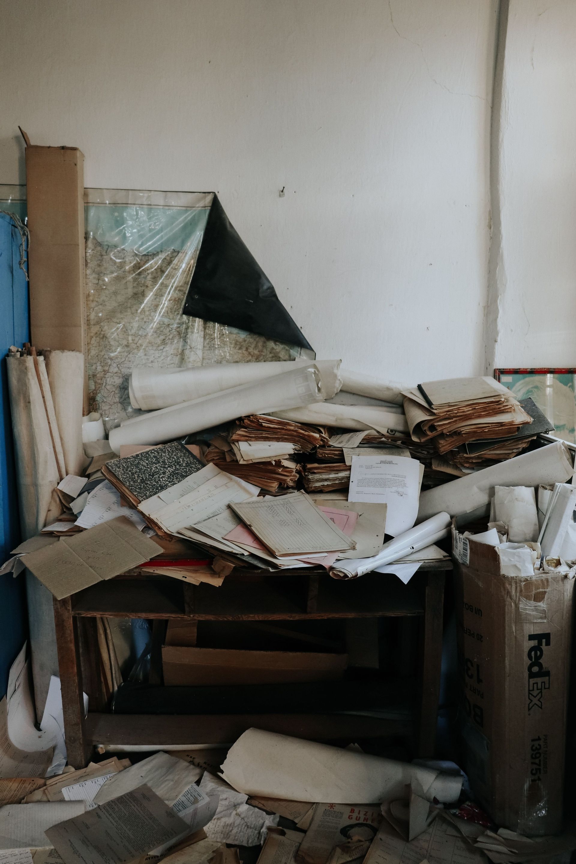 An abandoned desk piled with old papers and documents in a disorganized setting.