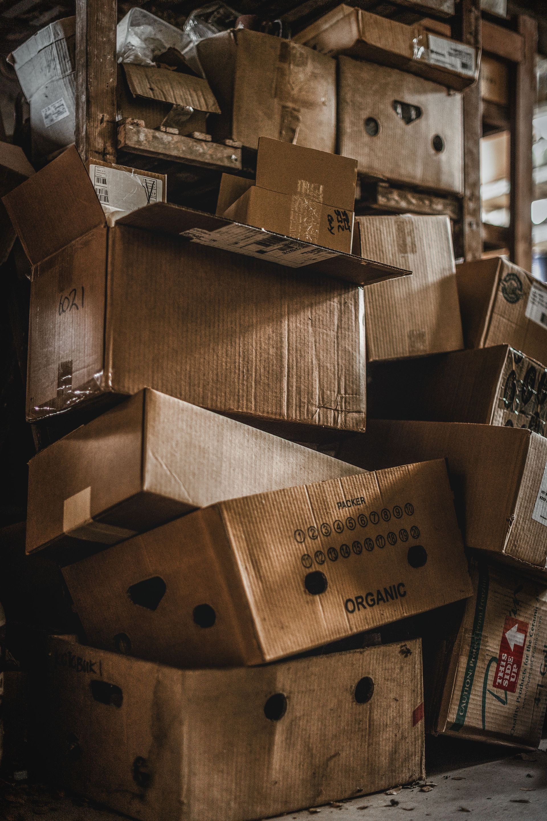 A stack of various cardboard boxes inside a cluttered warehouse environment.